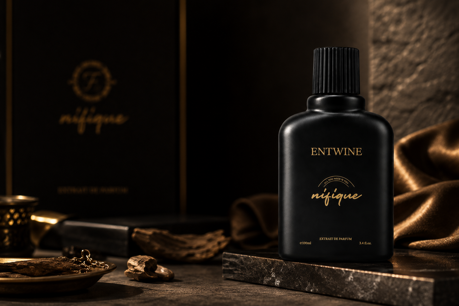 A black bottle of ENTWINE nifique decottage de marinière with gold lettering, displayed on a dark stone slab with a matching branded box in the background and gold fabric draping around it.
